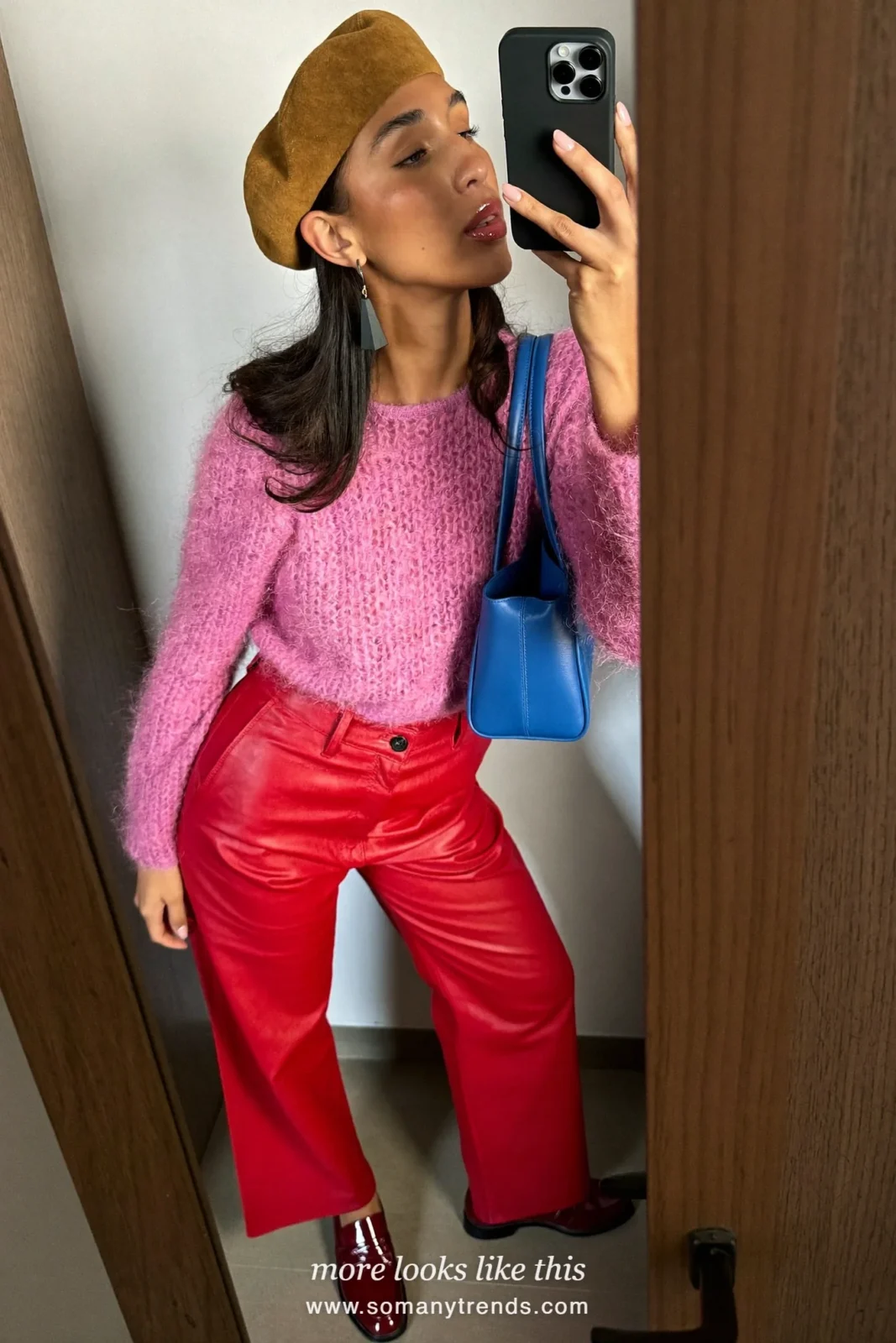Woman in a hot pink mohair knit, red soft matte leather straight pants, burgundy patent loafers and a small cobalt blue bag, look 3