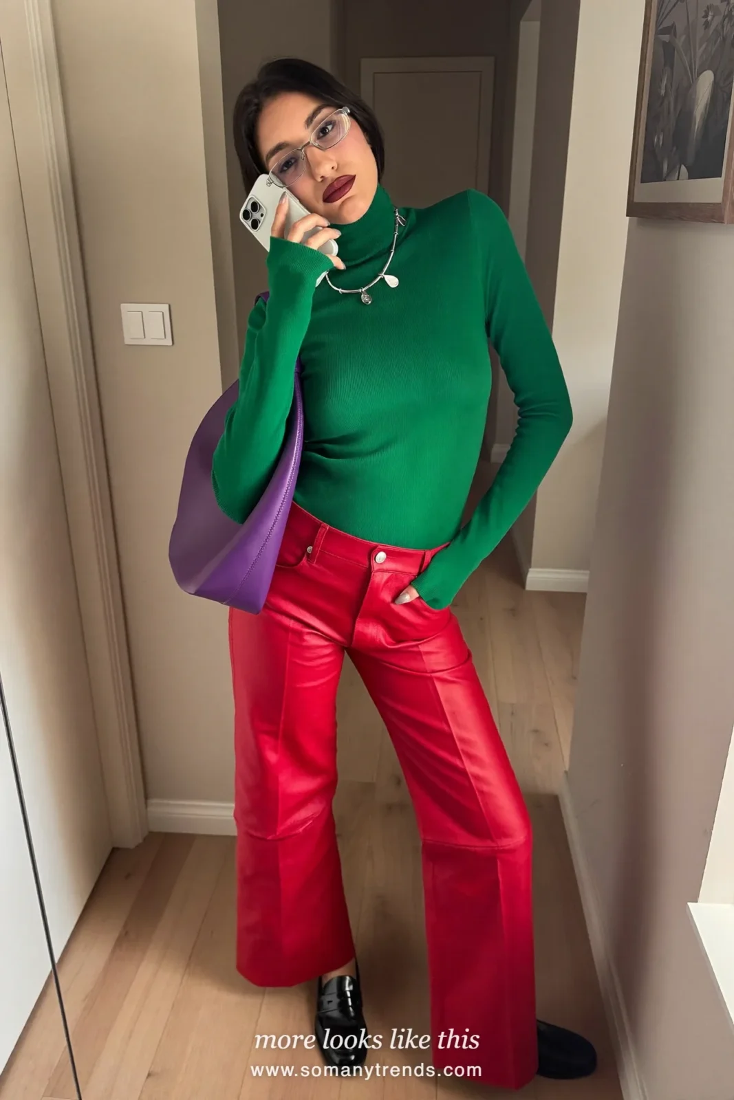 Woman in an emerald green fine-knit turtleneck, red soft matte leather straight pants, black patent loafers and a violet bag, look 6
