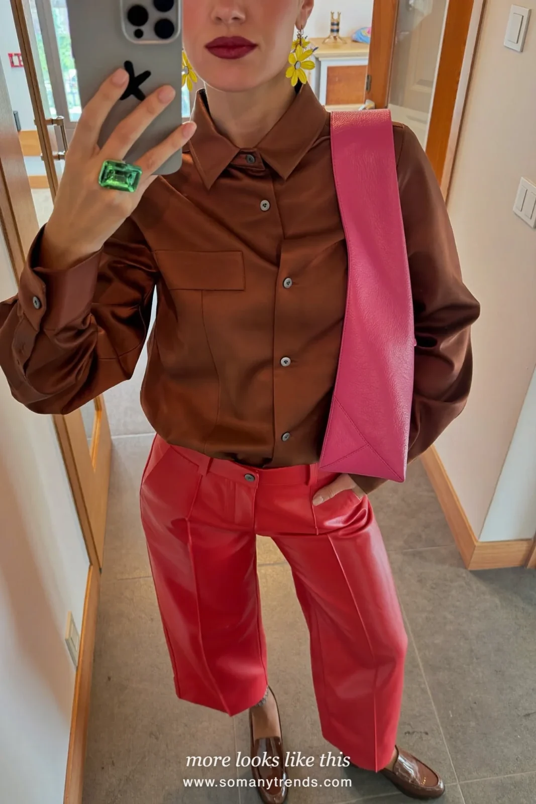 Woman in a chocolate brown satin blouse, red soft matte leather straight pants, brown patent loafers and a hot pink leather bag, look 15