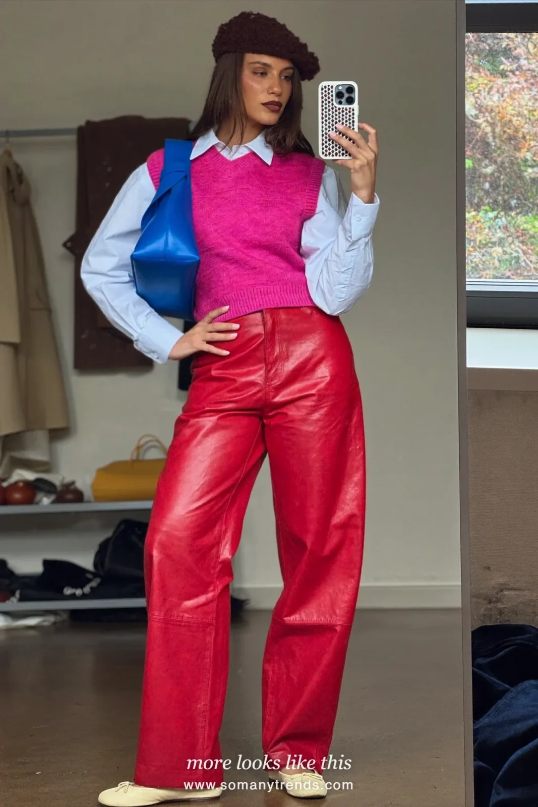Woman in a hot pink knit vest over a white shirt, red soft matte leather straight pants, cream flats and a cobalt blue bag, look 18
