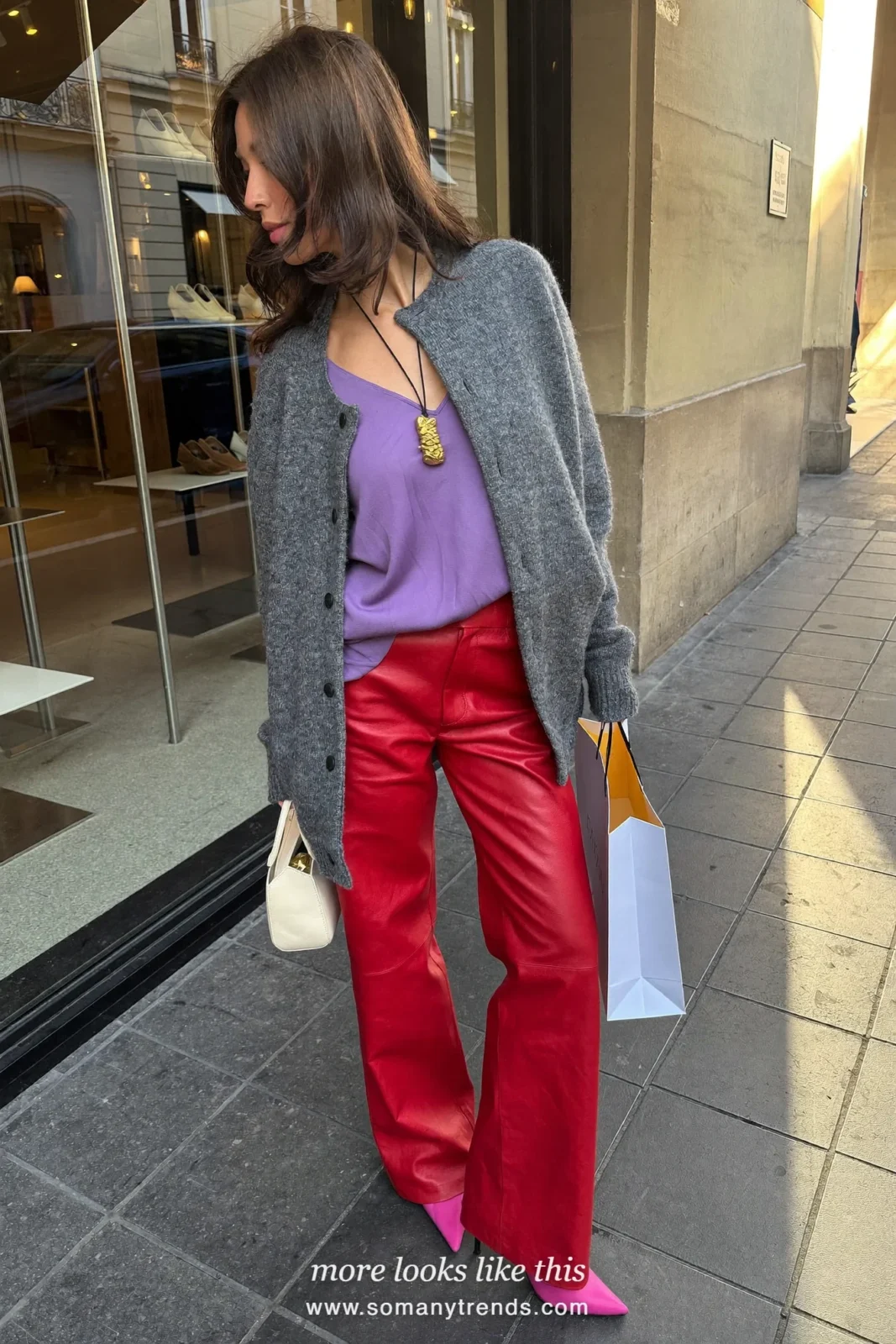 Woman in a lilac blouse under a gray cardigan, red soft matte leather straight pants, pink pointed pumps and a small cream bag, look 22