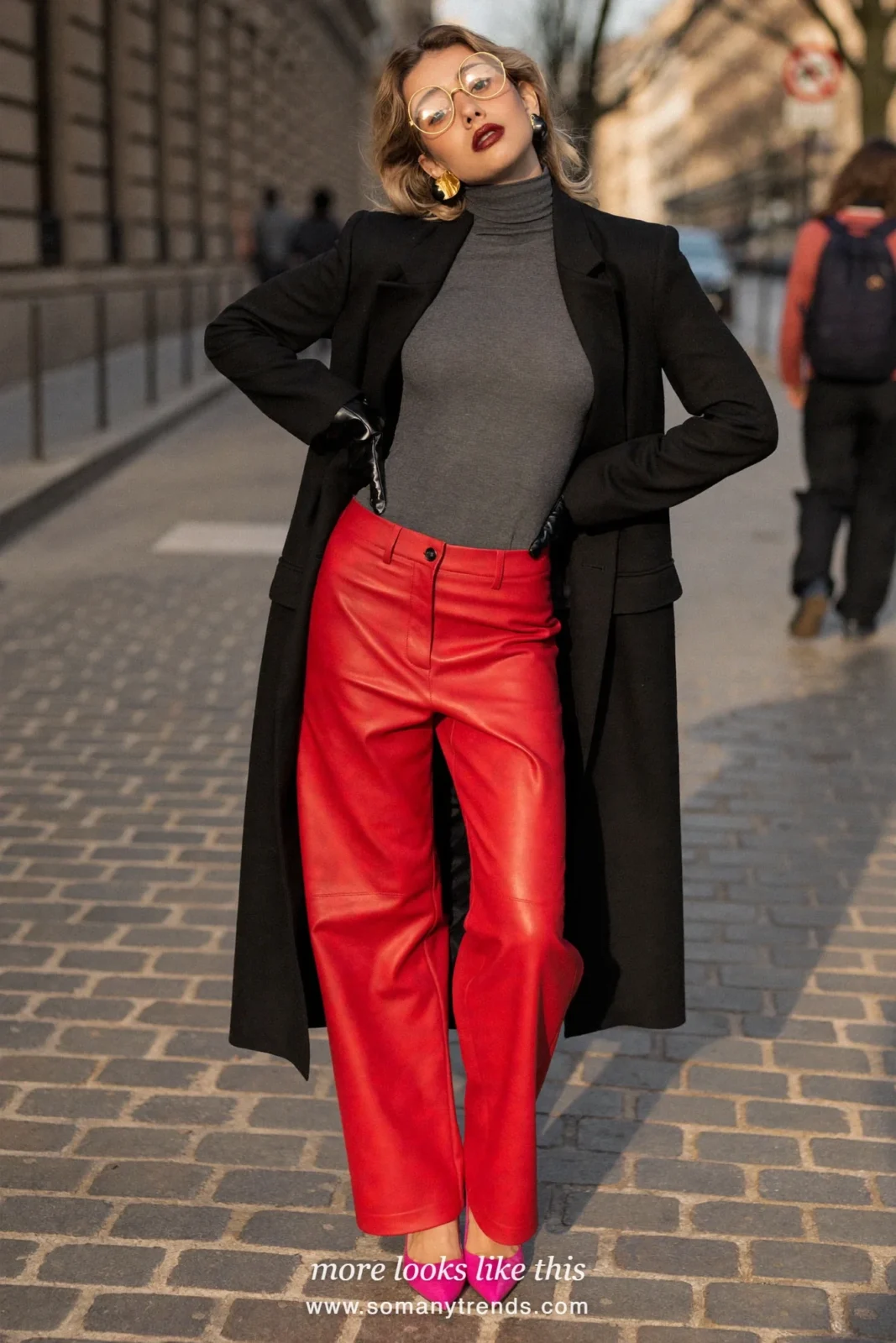 Woman in a gray turtleneck, red soft matte leather straight pants, hot pink patent pointed pumps and a long black coat worn open, look 26