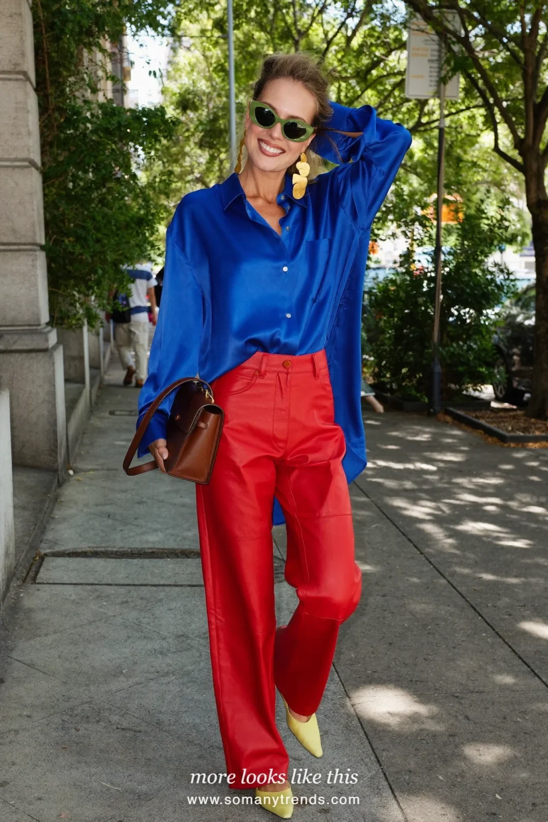 Woman in a cobalt blue satin shirt, red soft matte leather straight pants, butter yellow pointed flats and a brown top-handle bag, look 5