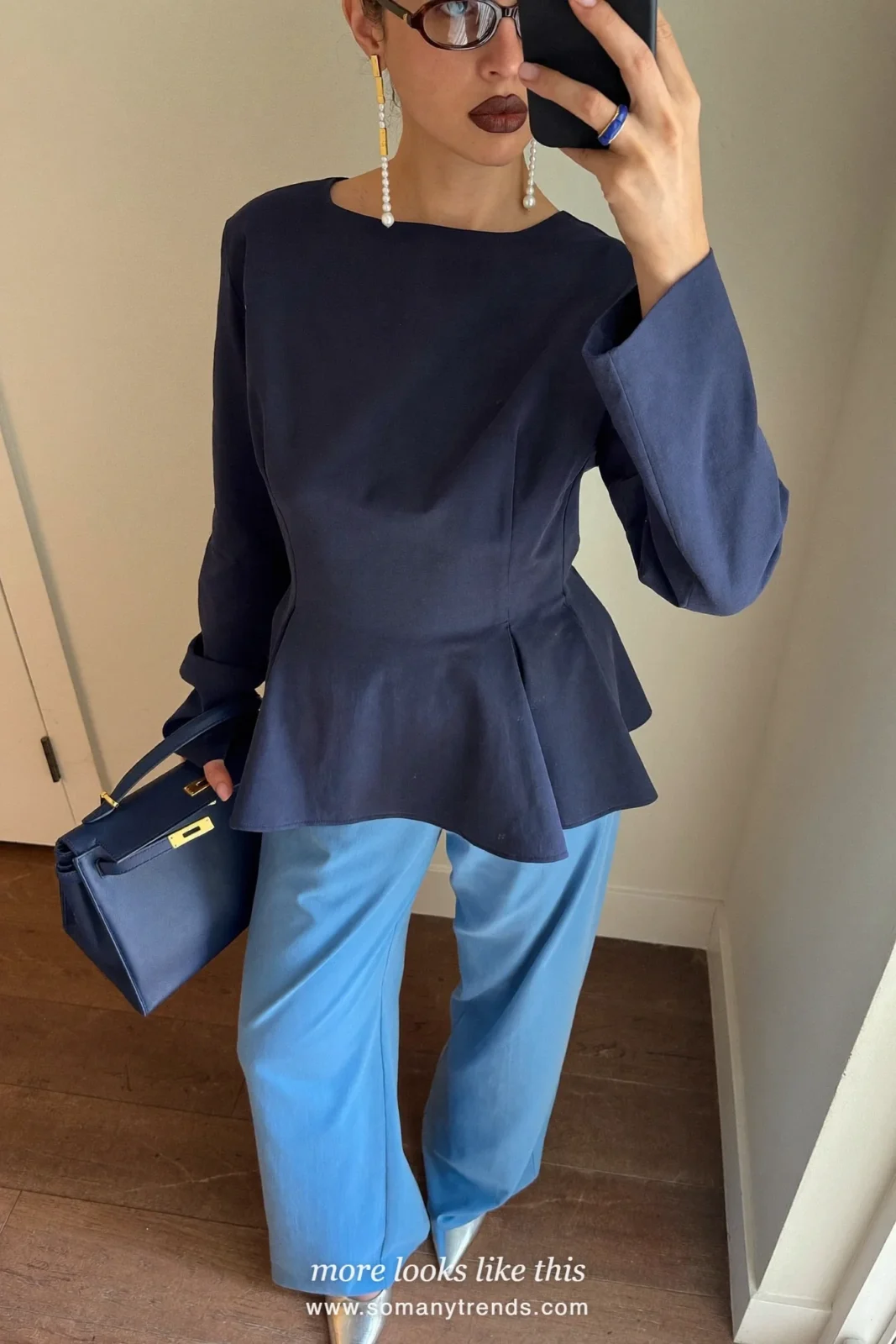 Petite woman in a navy peplum top, wide icy blue pants, silver pointed pumps and a navy bag, outfit 21