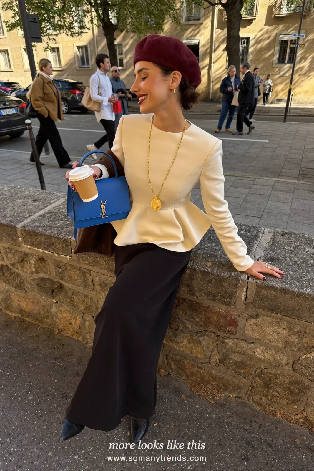 Petite woman in a cream peplum top, long black column skirt, black pointed boots and a cobalt blue bag, outfit 28