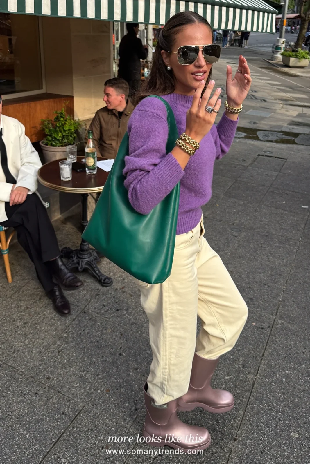 Woman in light metallic bronze short rain boots, straight cream pants, violet knit and emerald green tote, outfit 5