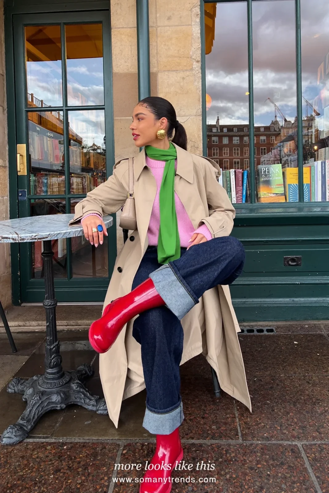Woman in cherry red short rain boots, dark straight jeans cuffed, pink knit, green scarf and beige mac worn open, outfit 14