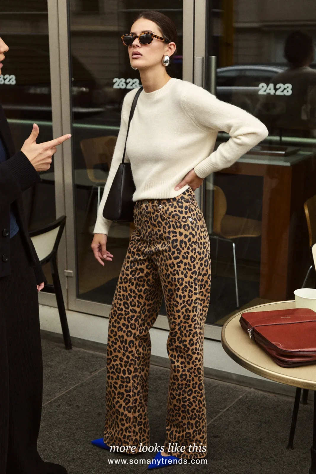 Woman in cream knit sweater, leopard print straight jeans, cobalt blue pointed pumps and black shoulder bag, outfit 19