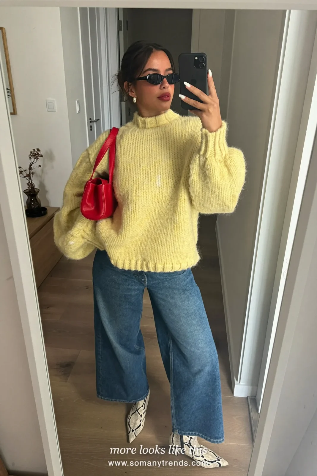 Woman in a butter yellow knit, straight blue jeans, black and cream snake print pointed ankle boots and a cherry red shoulder bag, outfit 3