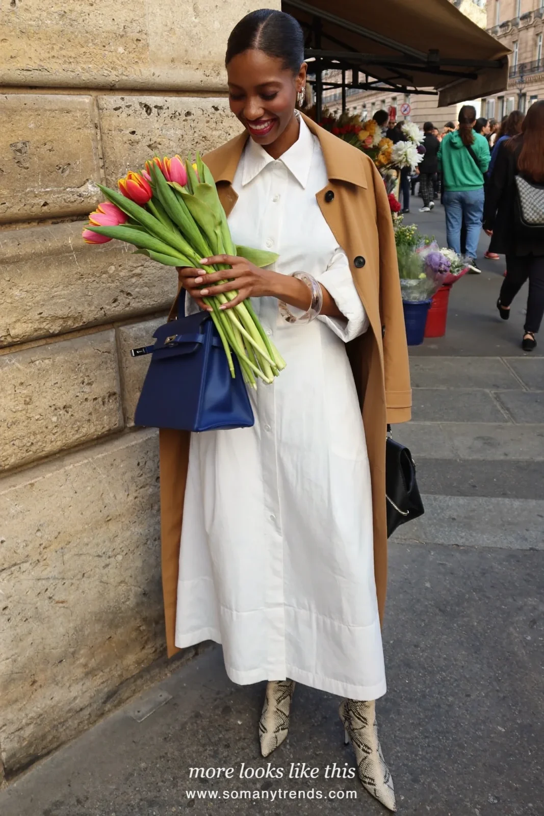 Woman in a white shirt dress, black and cream snake print ankle boots, a cobalt blue bag and a tan trench coat worn open, outfit 9