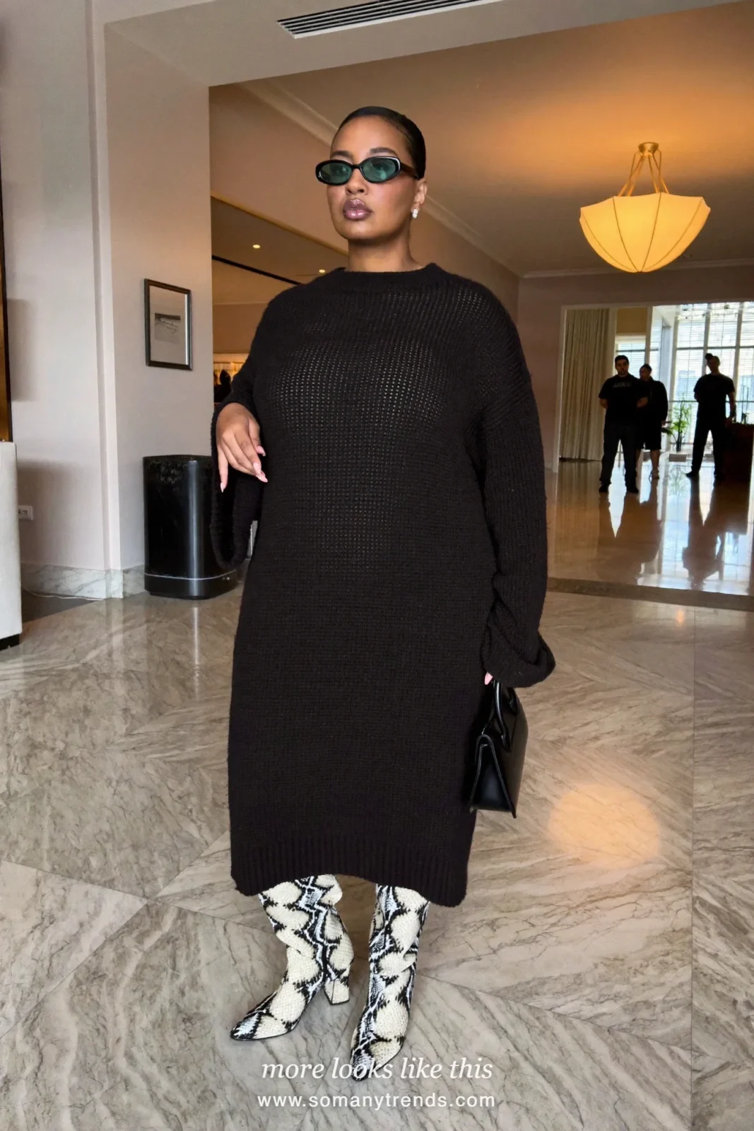 Woman in a loose black knit midi dress and black and cream snake print knee-high boots, outfit 13