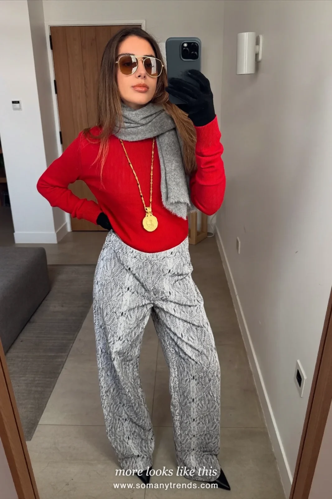 Woman in a cherry red knit, gray and white snake print wide pants, black ankle boots, a gray scarf and gloves, outfit 15