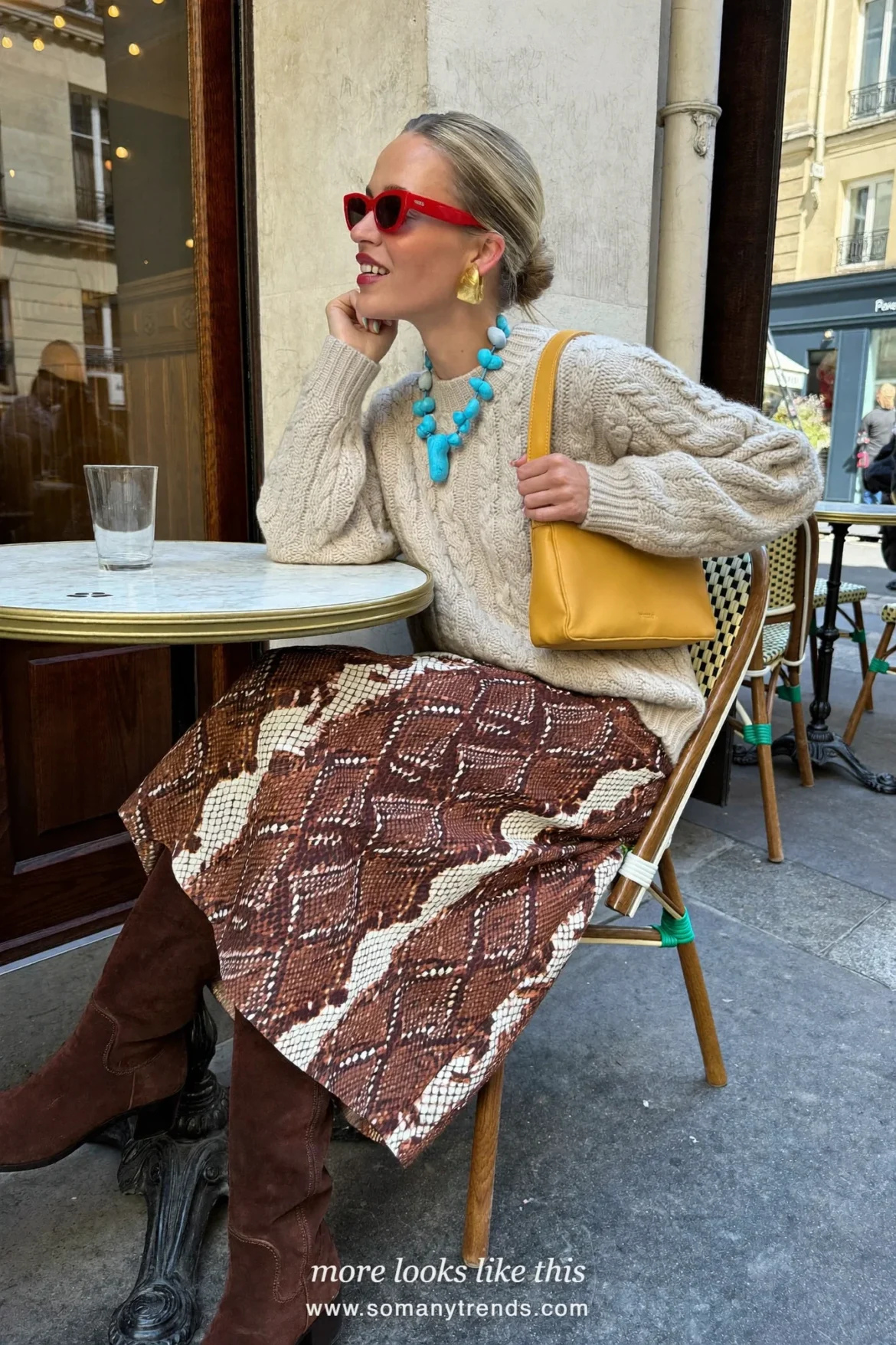 Woman in a cream chunky knit, rust brown and cream snake print midi skirt, brown suede knee boots and a butter yellow bag, outfit 17