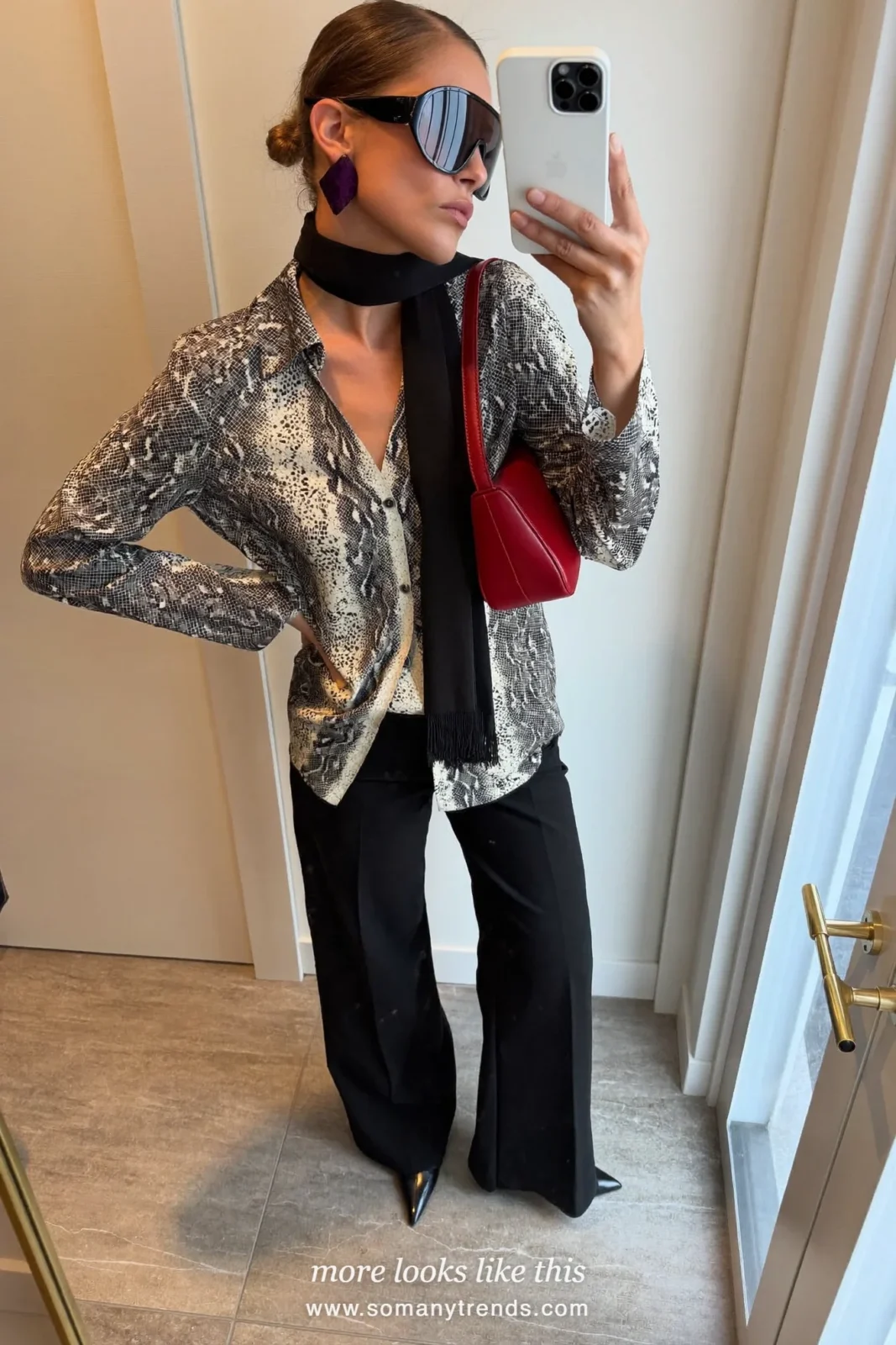 Woman in a black and cream snake print top, black wide pants, black pointed boots and a cherry red bag, outfit 18