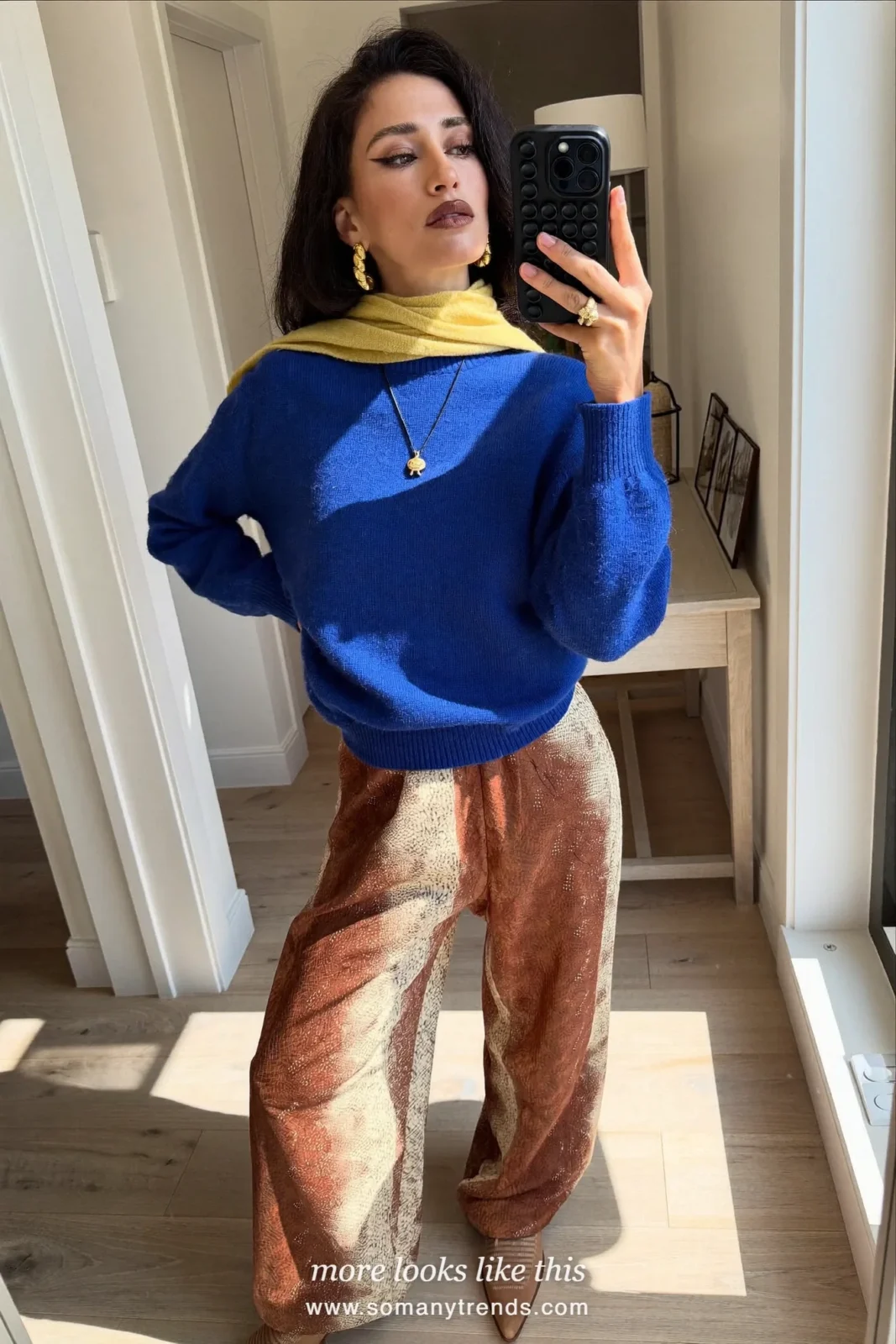 Woman in a cobalt blue knit, rust brown and cream snake print wide pants, tan pointed boots and a butter yellow scarf, outfit 24