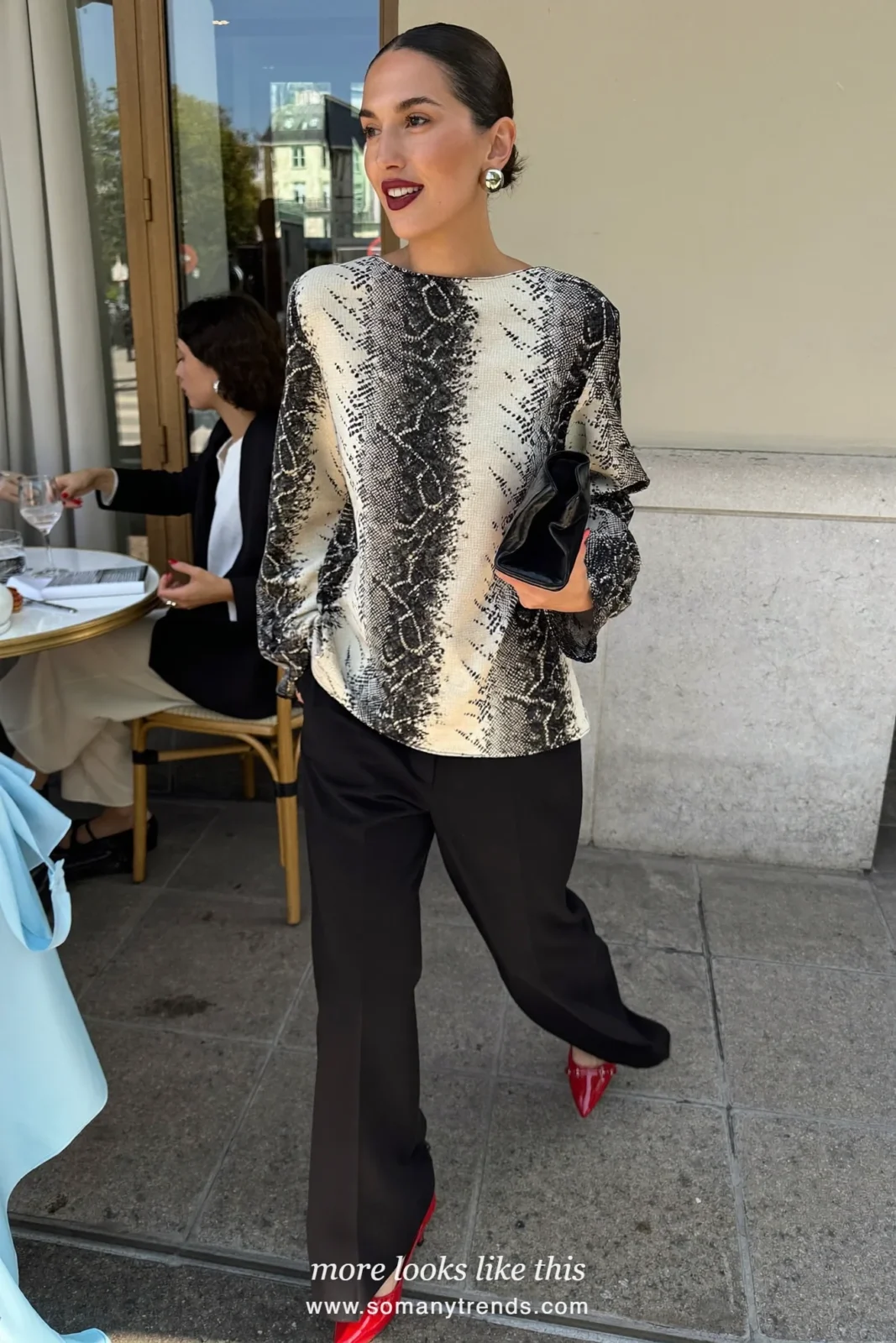 Woman in a black and cream snake print long sleeve top, wide black pants, cherry red heels and a black clutch, outfit 26