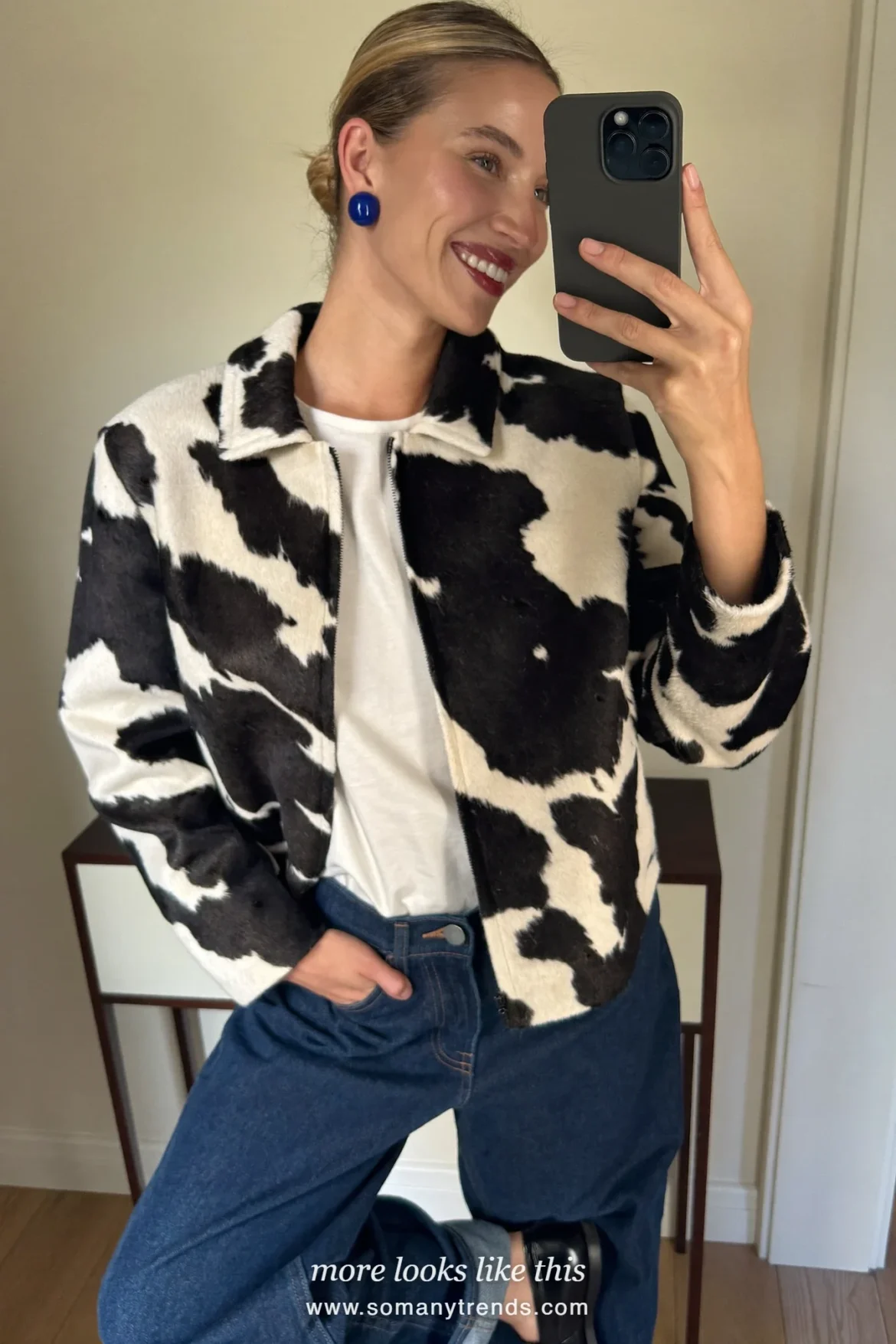 Woman in a short black and white cow print jacket over a white tee with dark blue straight jeans and black loafers, outfit 15
