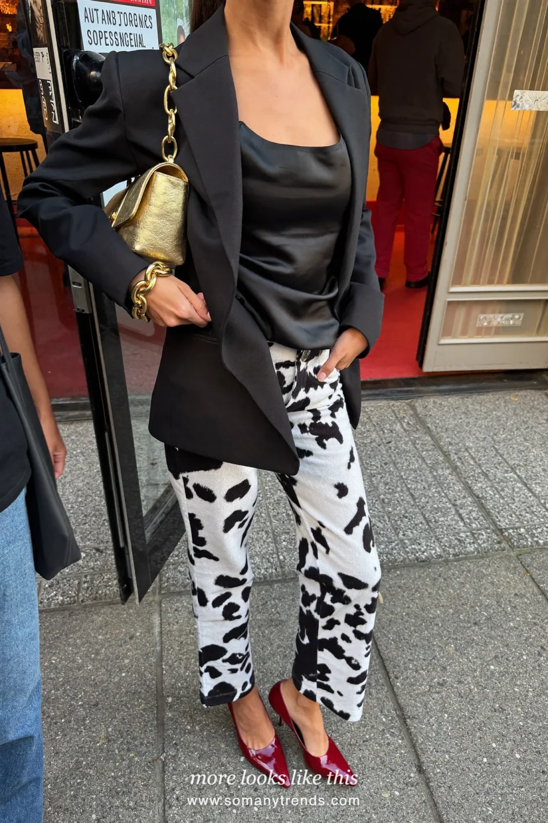 Woman in black and white cow print wide pants with a black satin cami, short black blazer, cherry red pumps and a small gold bag, outfit 25