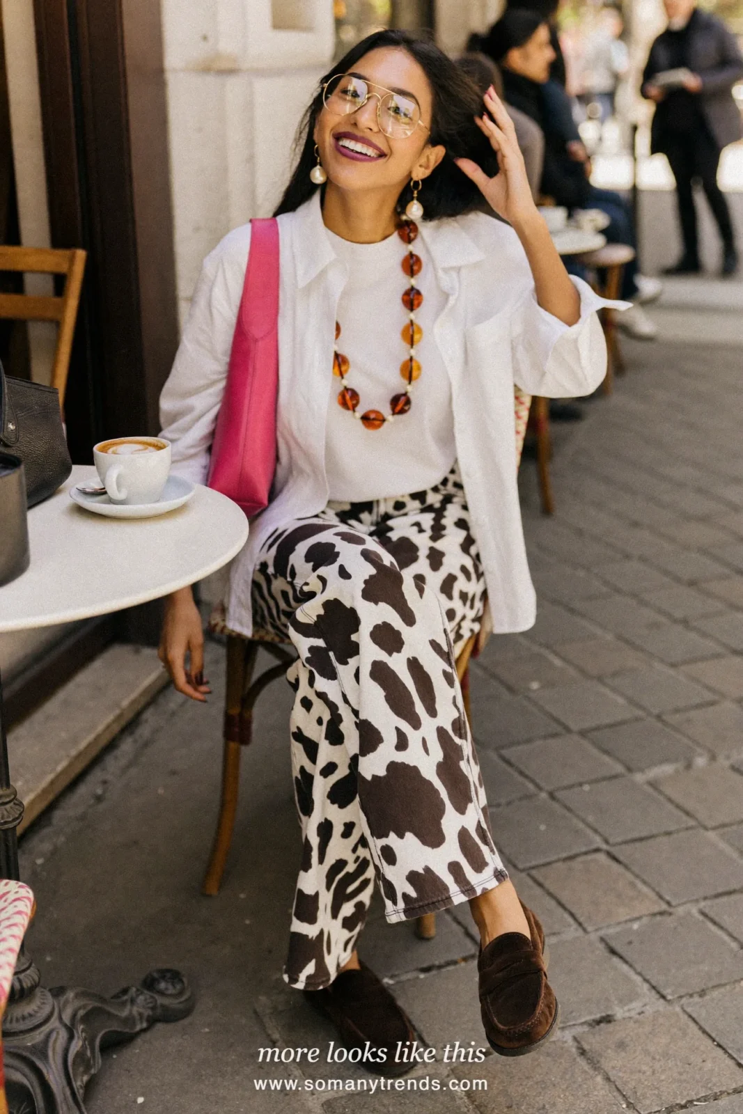 Woman in black and white cow print straight jeans with a white poplin shirt, white tee, chocolate brown suede loafers and a hot pink bag, outfit 26