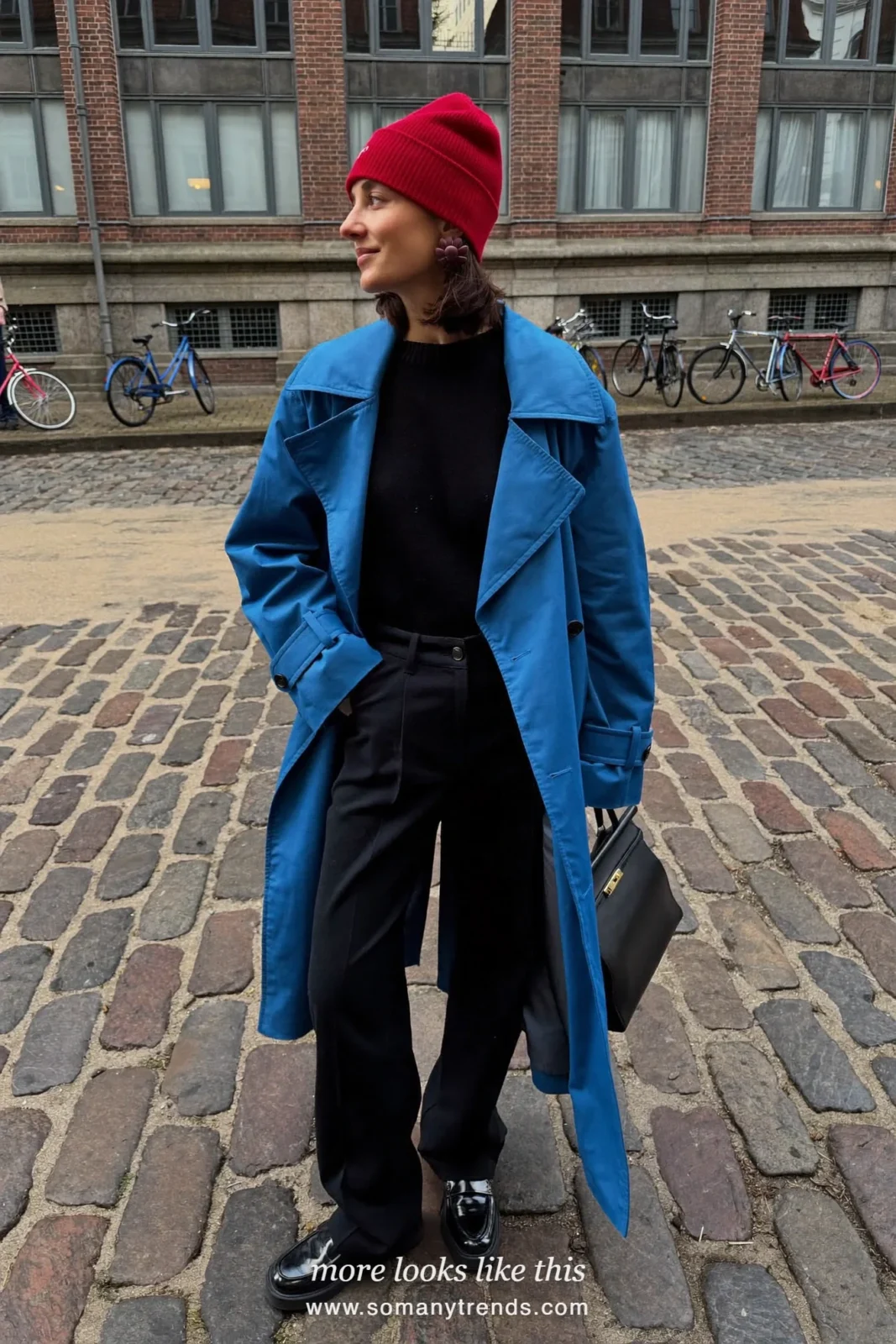 Woman in a long cobalt blue trench coat over a black knit top, black wide-leg pants and black leather loafers with a black bag, outfit 1