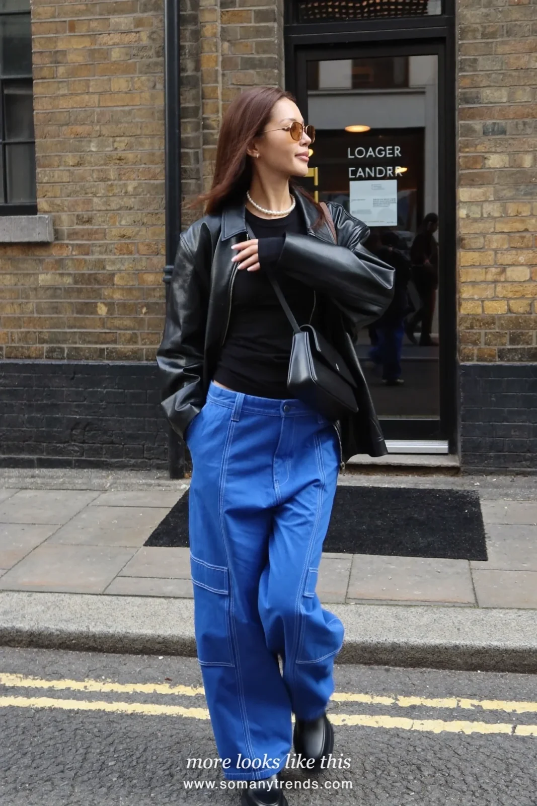 Woman in cobalt blue cargo pants, black leather jacket, black knit top and chunky black boots, outfit 5