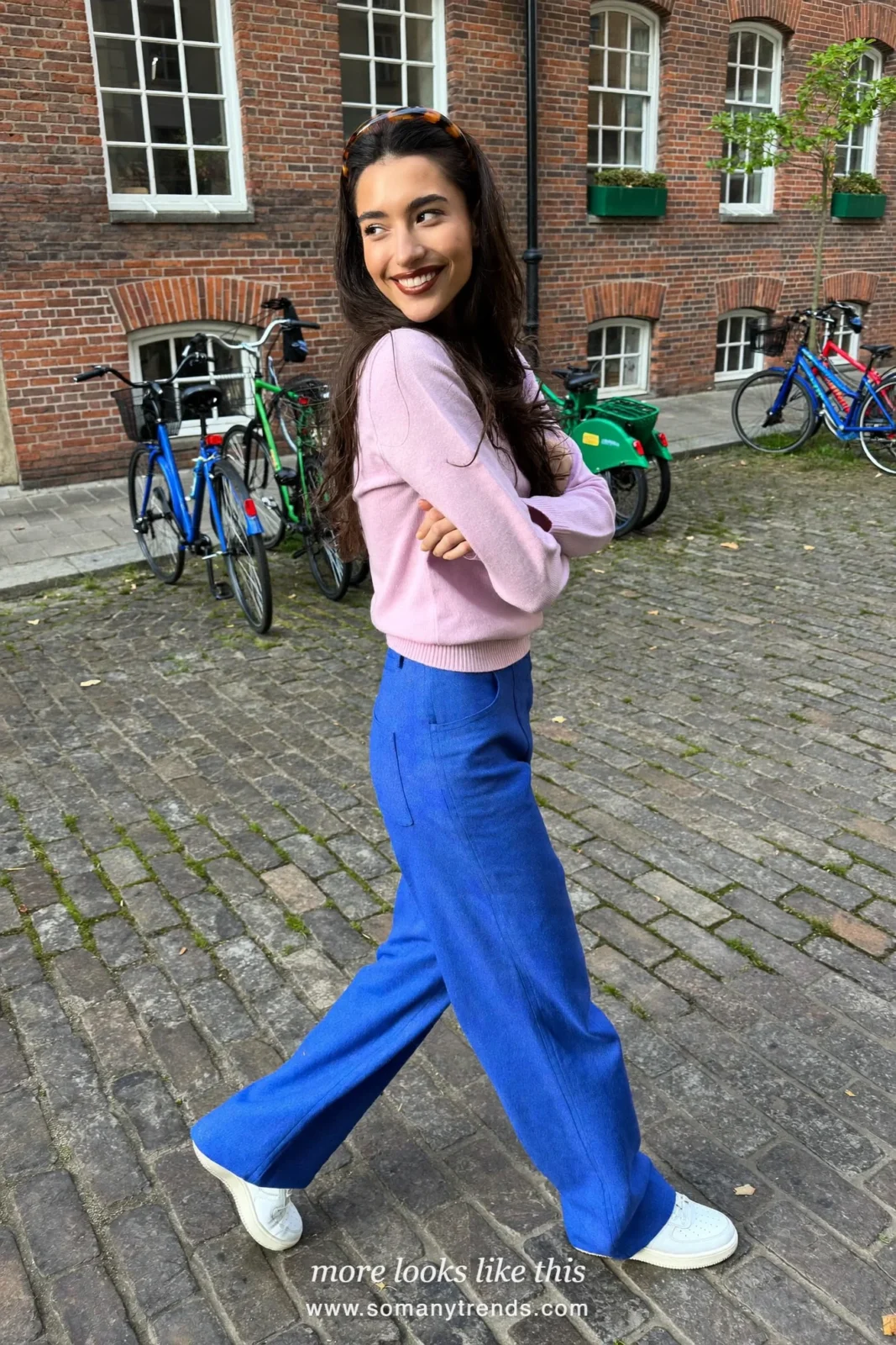 Woman in a pink knit sweater, cobalt blue wide-leg pants, white sneakers and a cream bag, outfit 20