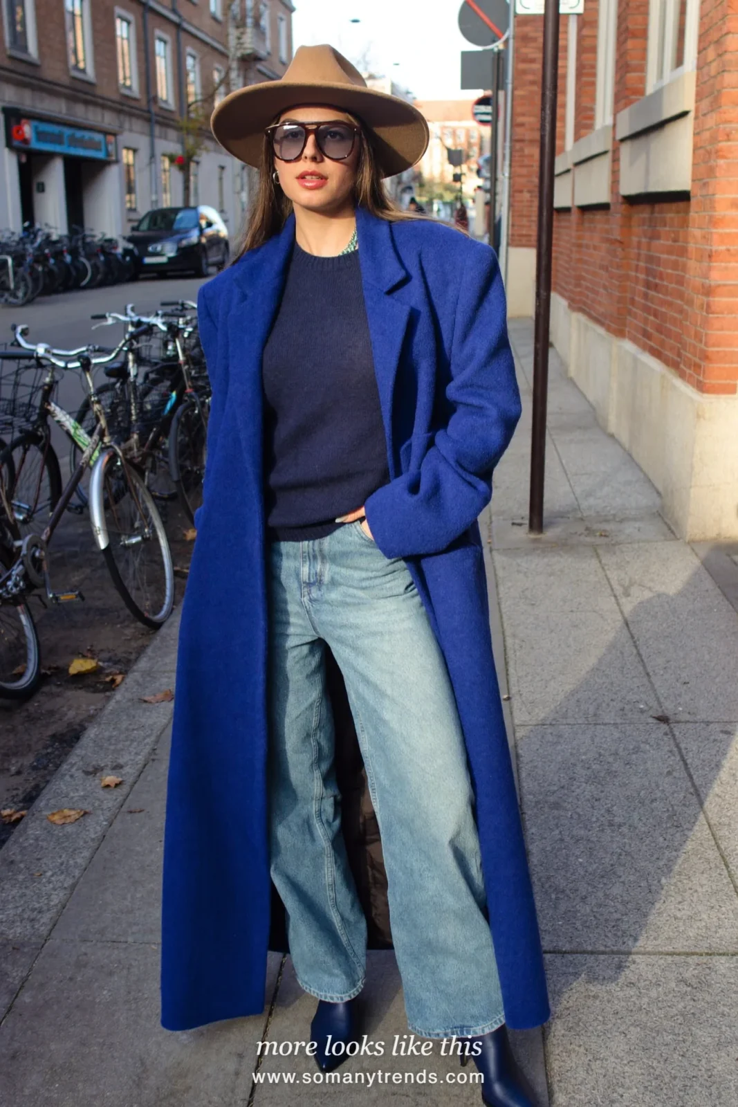 Woman in a long cobalt blue coat over a navy knit and pale blue jeans with navy boots, outfit 26