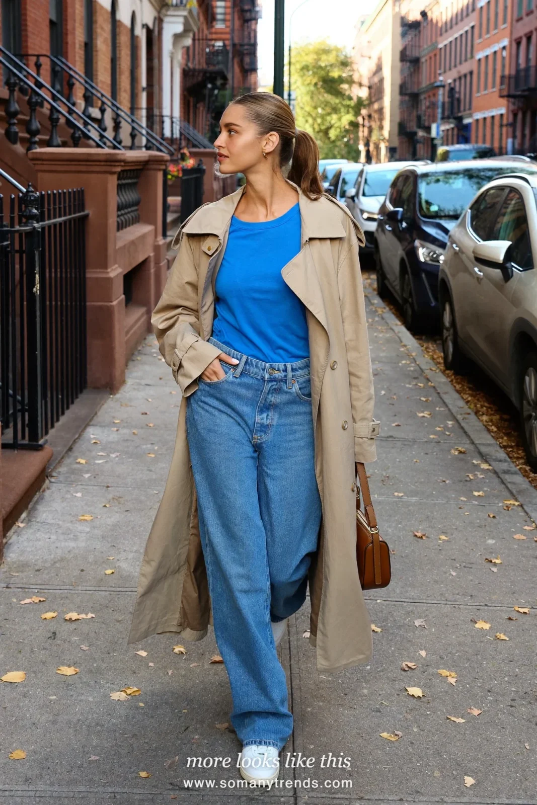 Woman in a cobalt blue tee, wide-leg jeans, long beige trench coat and white sneakers, outfit 29