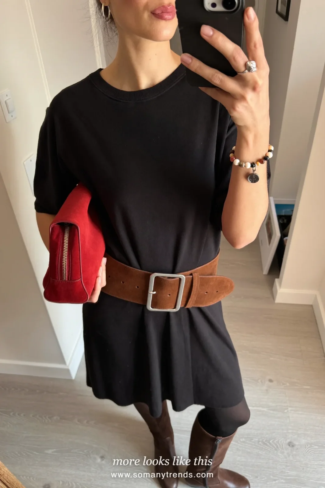 Woman in a black knit midi dress with a chocolate suede belt, brown suede knee boots and a cherry red clutch, look 3