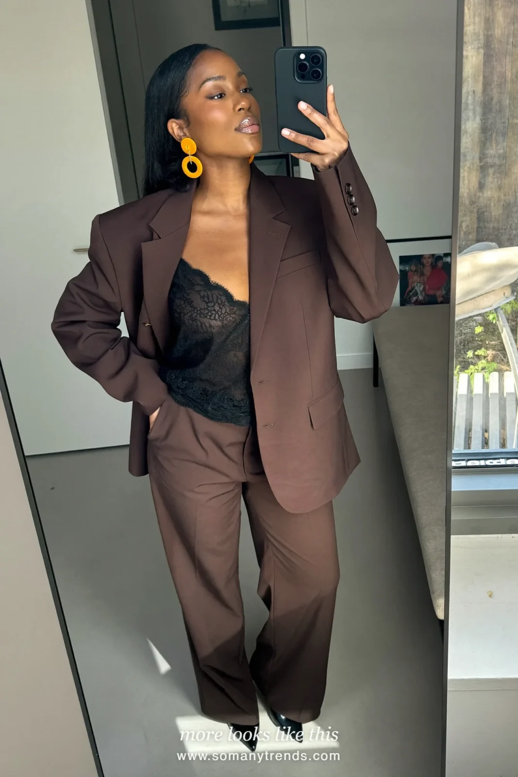 Woman in a chocolate brown oversized suit with a black lace camisole and black pointed pumps, look 6
