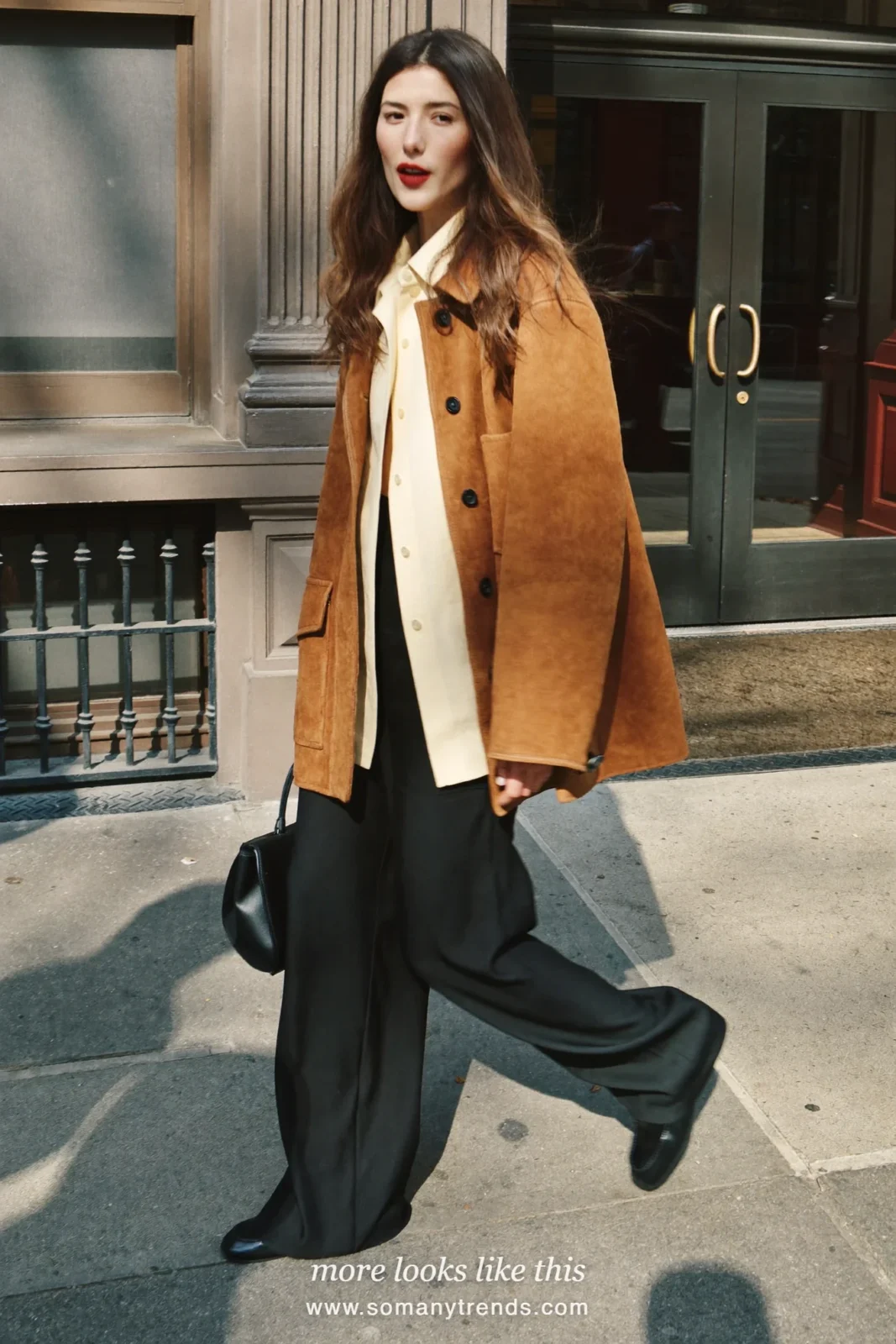 Woman in a brown suede chore jacket, cream shirt, black wide-leg pants and black loafers, look 7