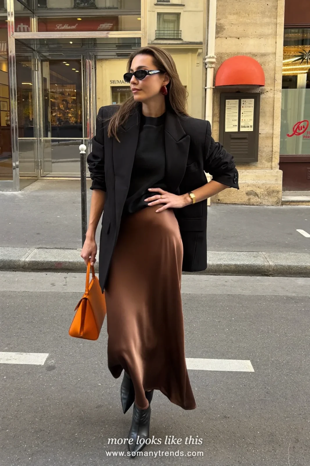 Woman in a black oversized blazer, bronze brown satin slip maxi skirt, black pointed ankle boots and a tangerine bag, look 8