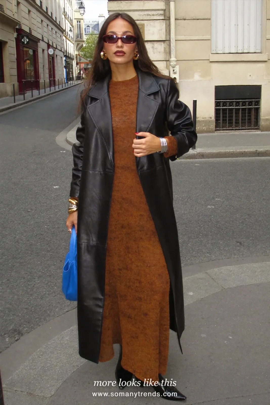 Woman in a loose rust brown knit maxi dress with a black leather coat, black boots and a cobalt blue bag, look 20