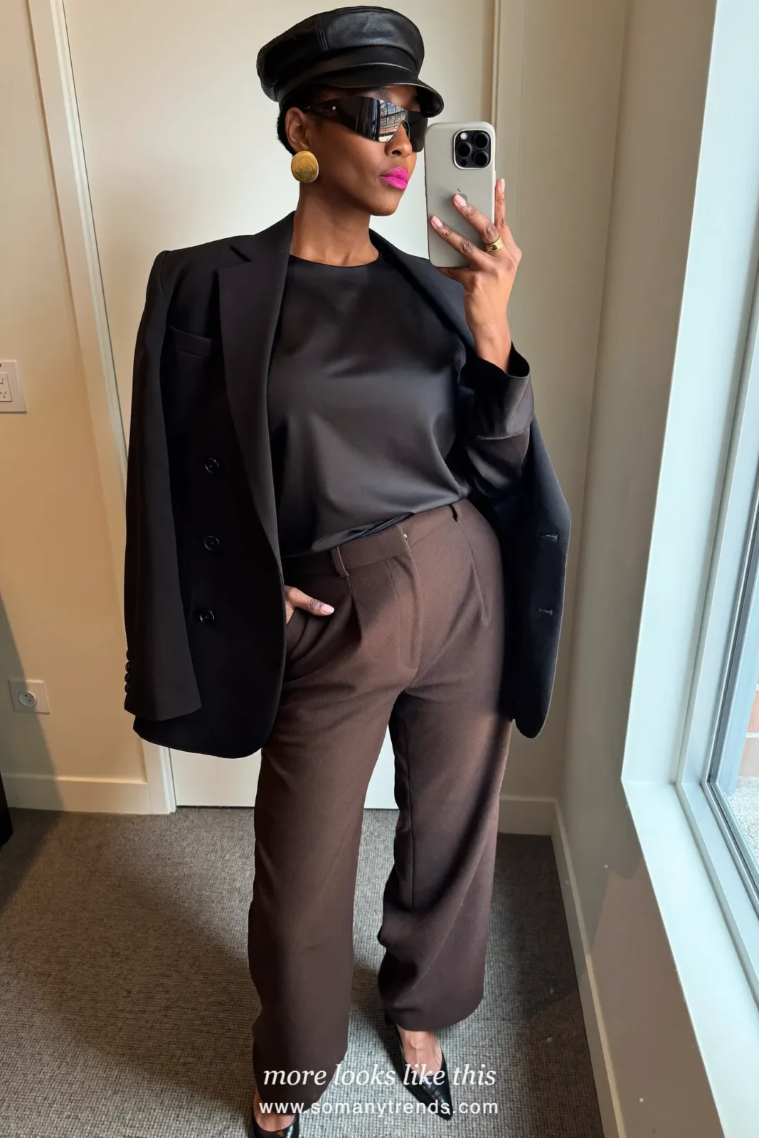 Woman in a black satin top, chocolate brown wool wide-leg pants, a black blazer, black pointed heels and a cherry red clutch, look 21