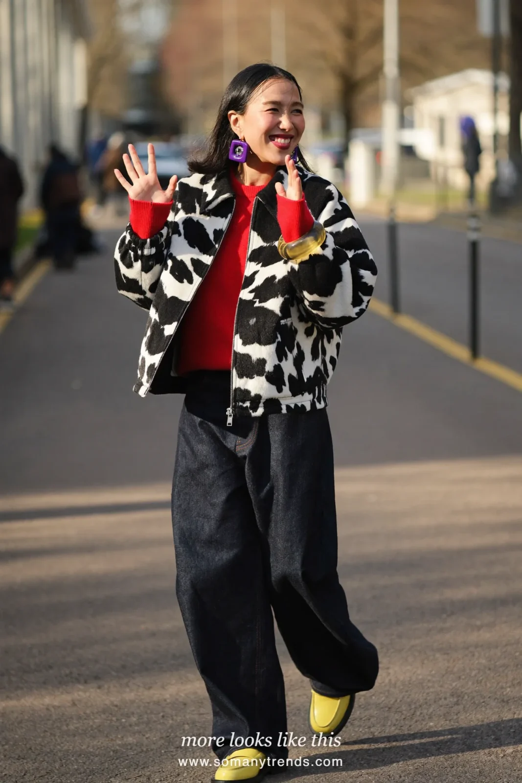 Woman in a short black and white cow print jacket over a cherry red knit with dark blue straight jeans and butter yellow patent loafers, outfit 1