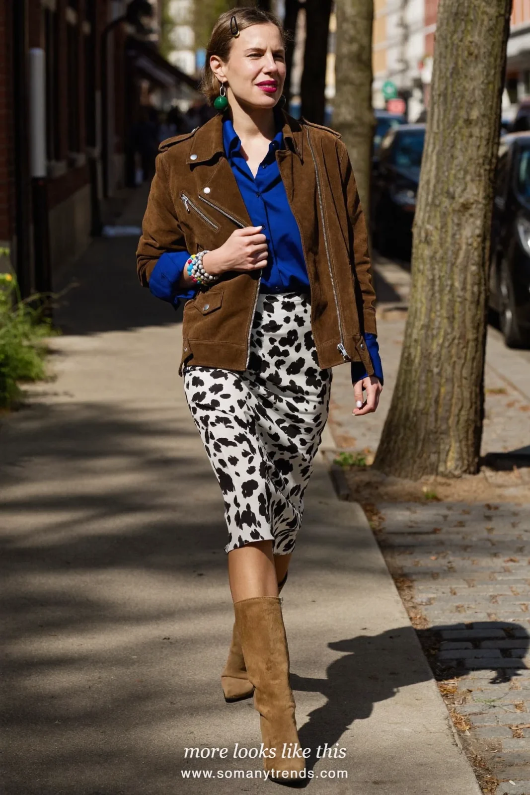 Woman in a black and white cow print midi slip skirt with a cobalt blue satin shirt, chocolate brown suede jacket and tan boots, outfit 8