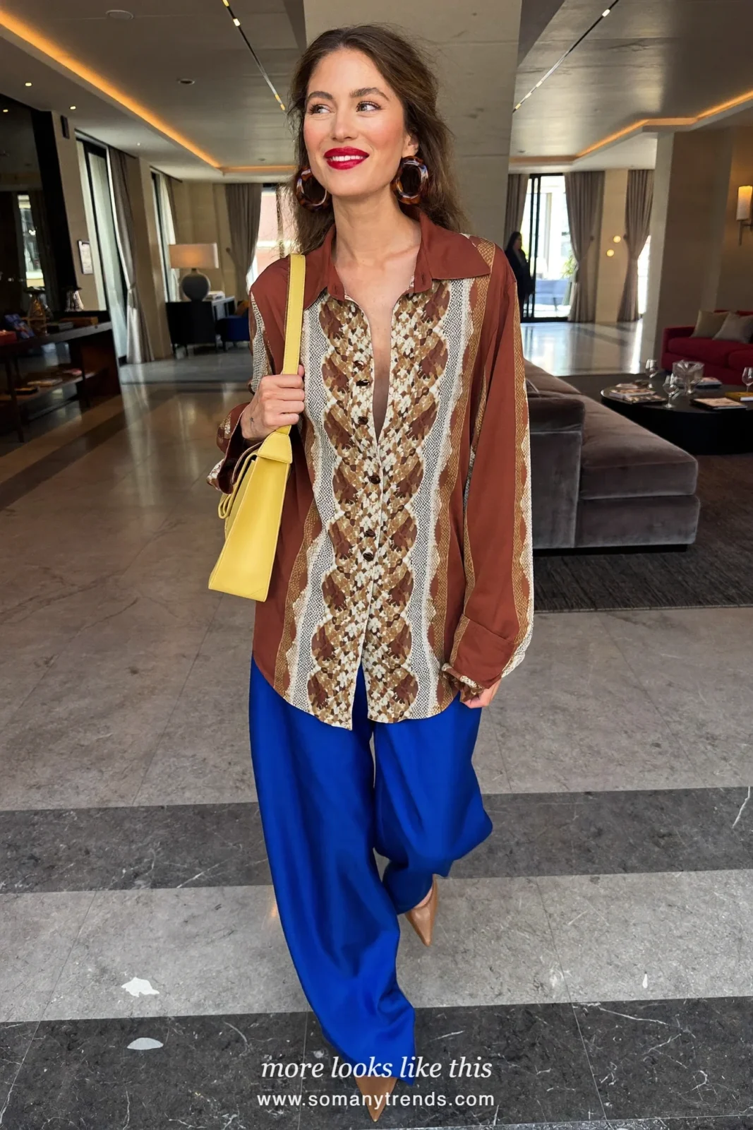 Woman in a rust brown and cream snake print silk blouse, cobalt blue wide-leg trousers, tan pointed pumps and a butter yellow bag, outfit 7