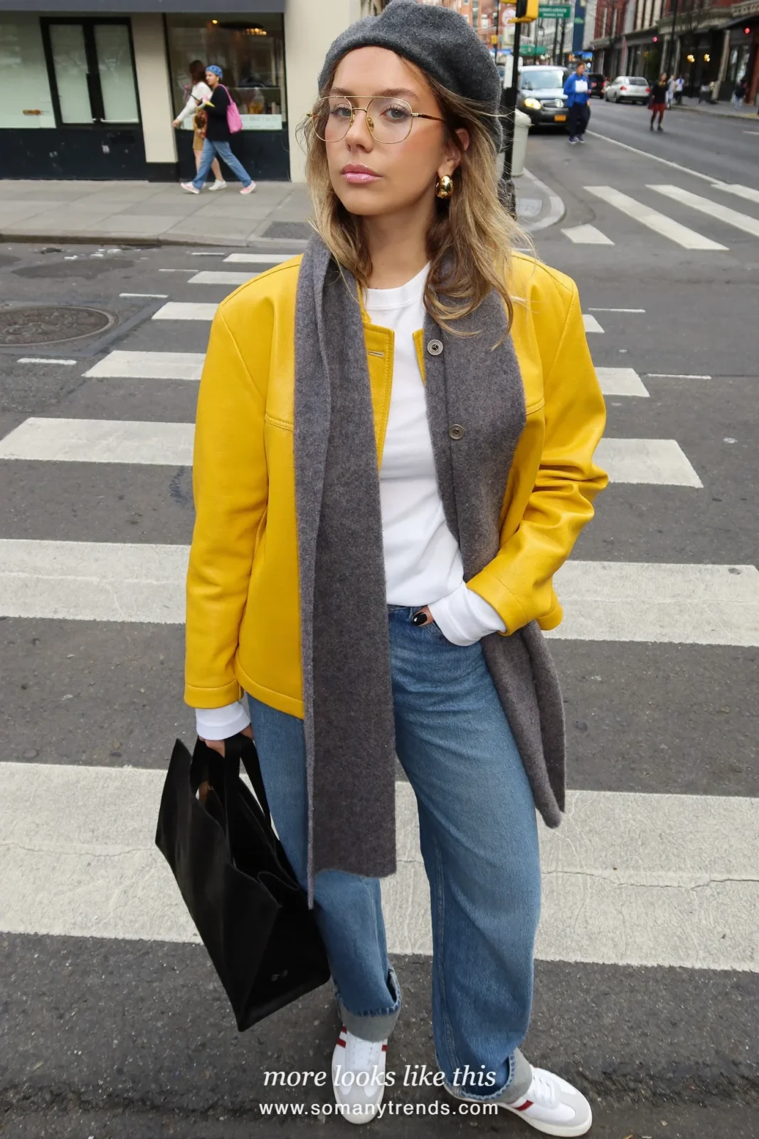 Woman in a lemon yellow leather jacket, white tee, mid-blue barrel jeans, gray scarf and white sneakers at a New York crosswalk, outfit 2