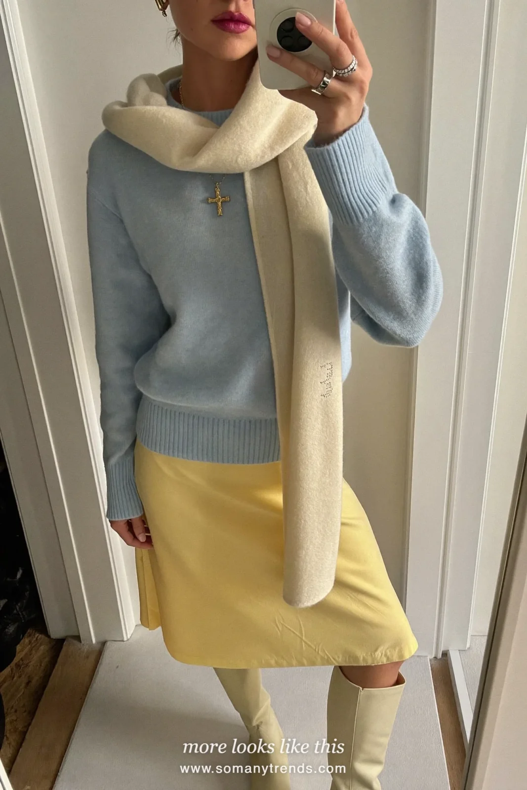 Woman in an ice blue knit sweater, butter yellow midi skirt, cream knee-high boots and a cream scarf, outfit 3