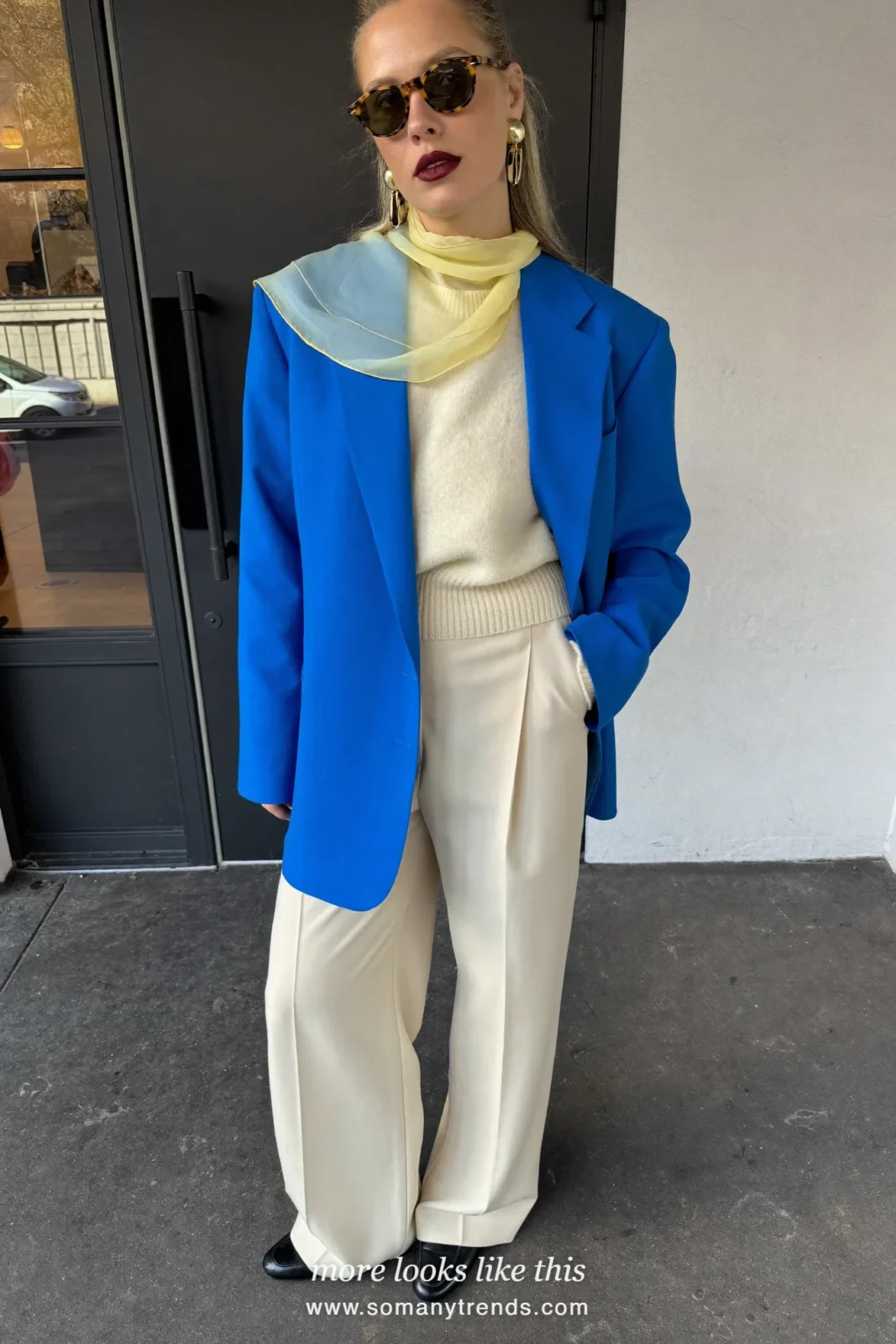 Woman in a cobalt blue oversized blazer, cream knit sweater, cream wide-leg pants, a lemon yellow scarf and black loafers, outfit 11