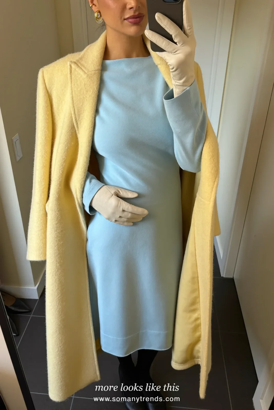 Woman in a long butter yellow wool coat, ice blue long-sleeve dress, black tights, black pumps and cream gloves at a restaurant entrance, outfit 24