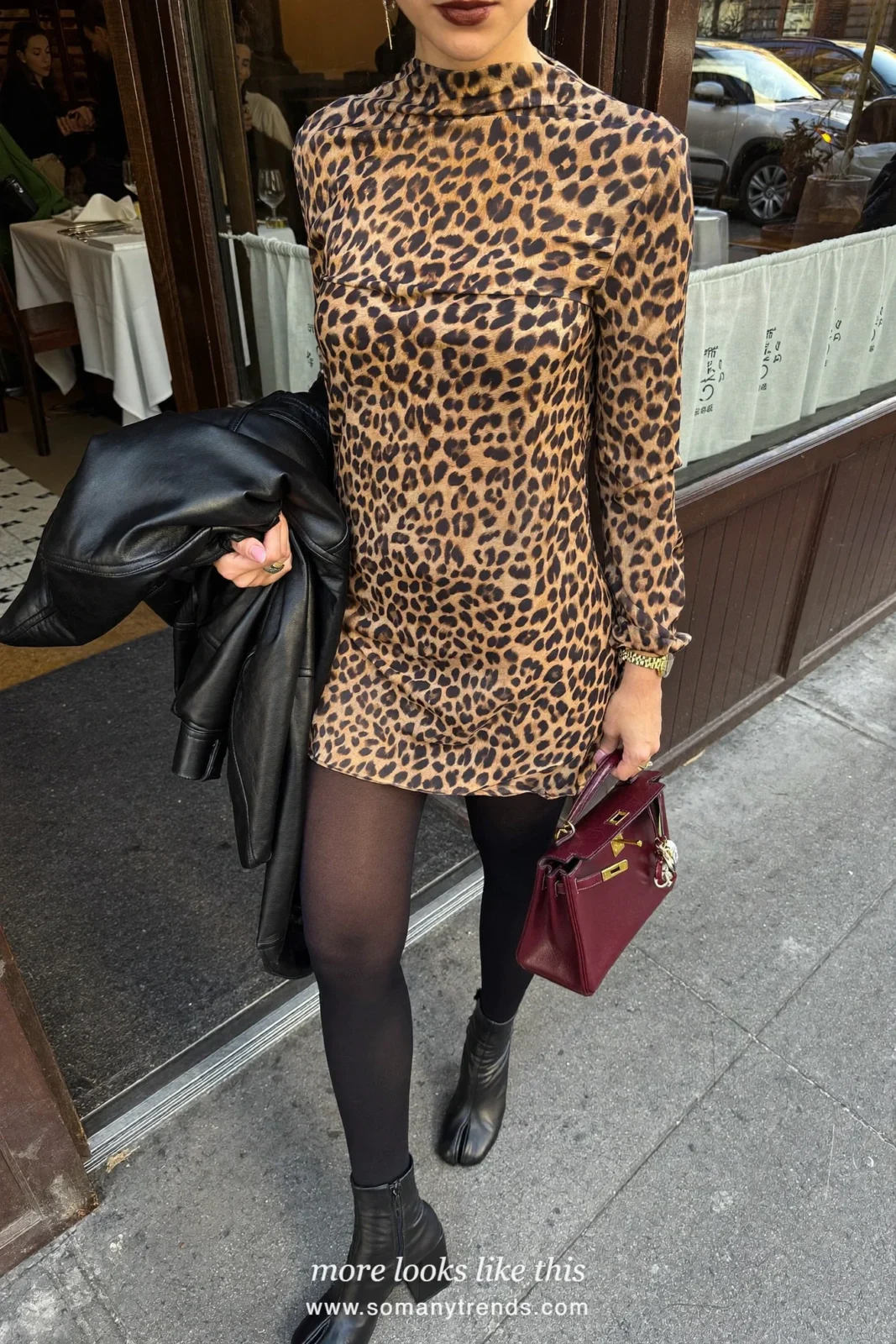 Woman in a leopard print silk mini dress, black tights, black ankle boots and a burgundy top-handle bag, outfit 16