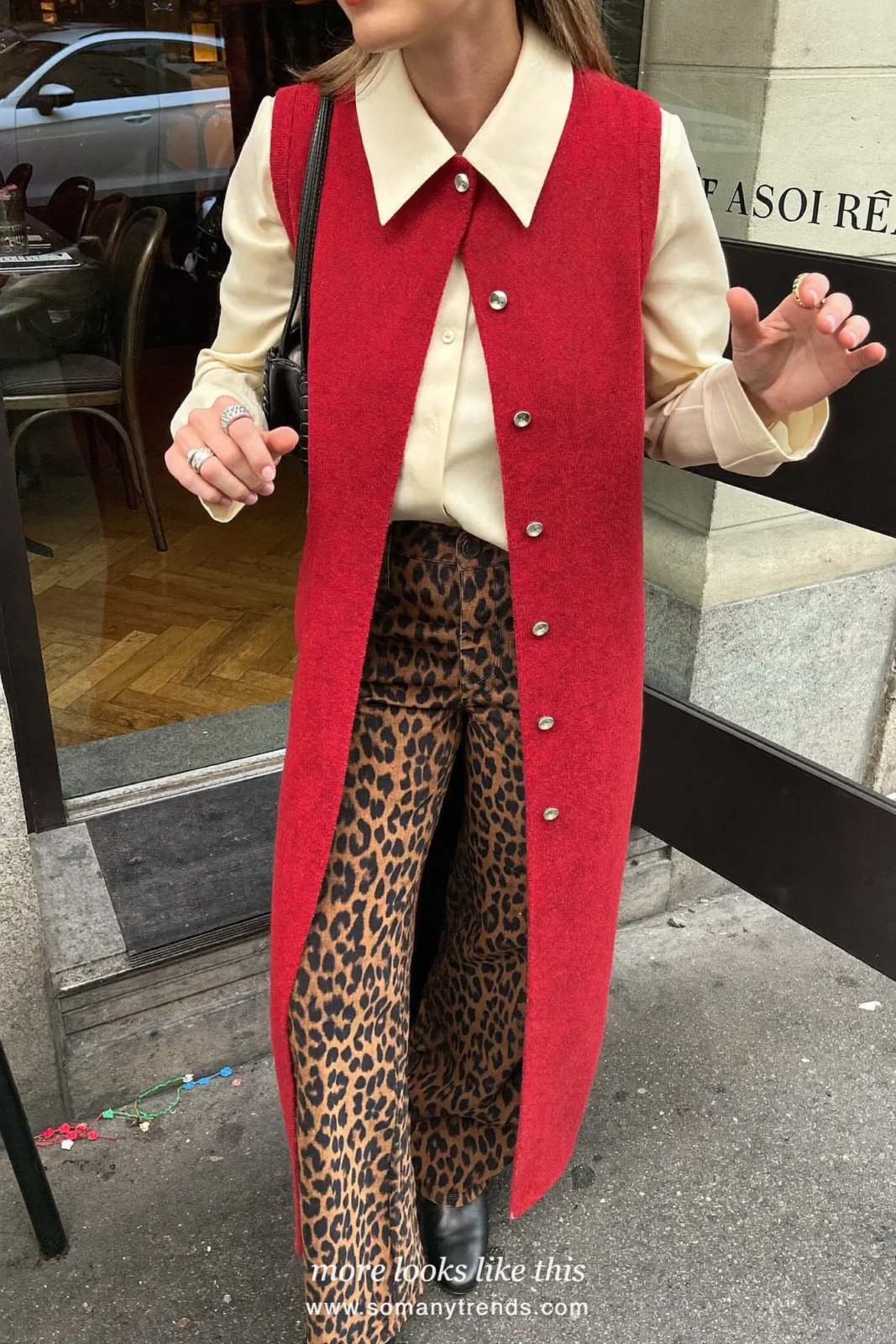 Woman in a red knit vest over a cream blouse, leopard print wide pants and black ankle boots, outfit 25