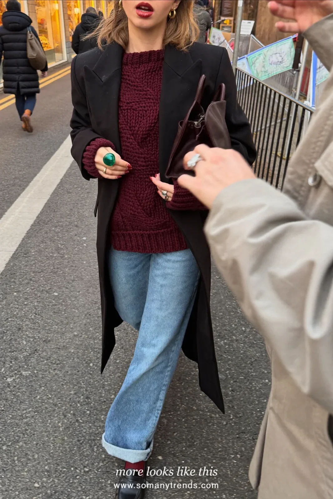 Woman in a long black tailored coat, burgundy knit sweater, light straight jeans, burgundy socks and black loafers, outfit 7