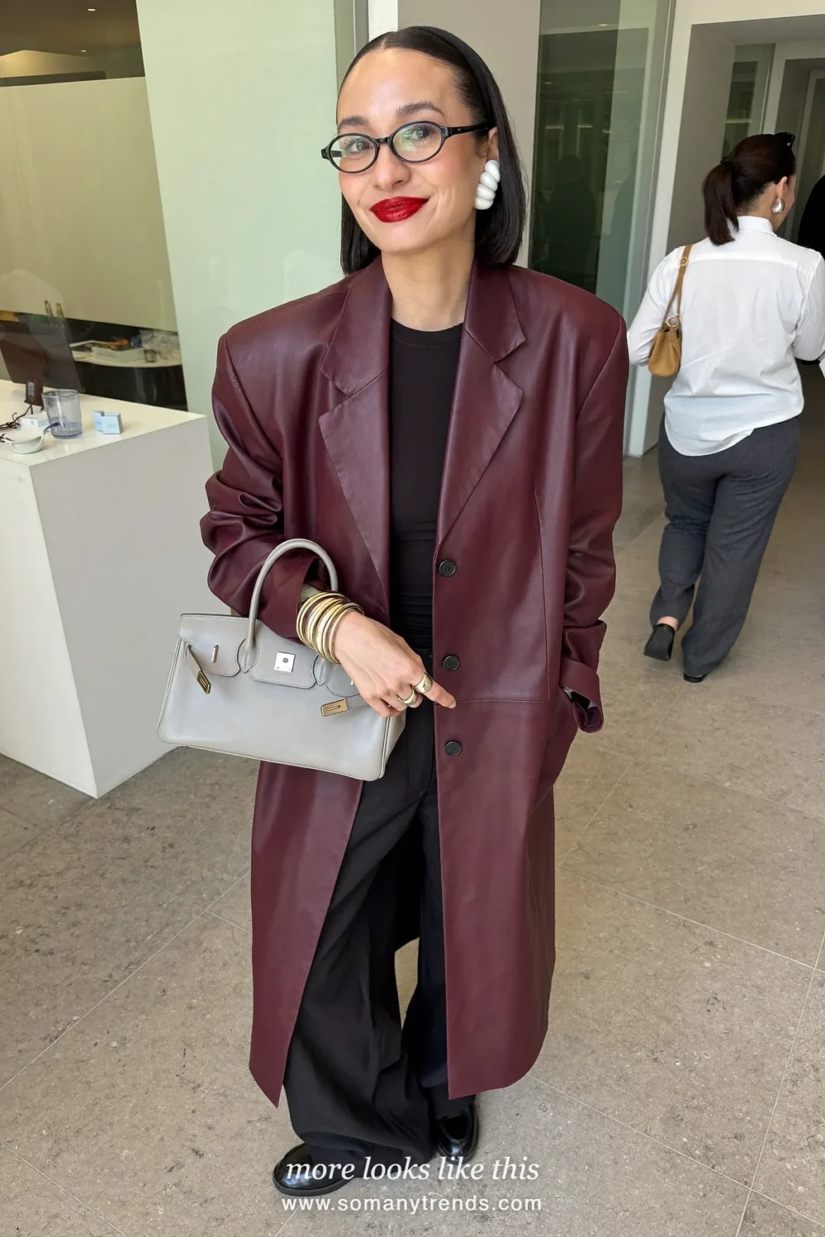 Woman in a burgundy oversize blazer, black top, black straight pants, black loafers and a gray bag, outfit 17