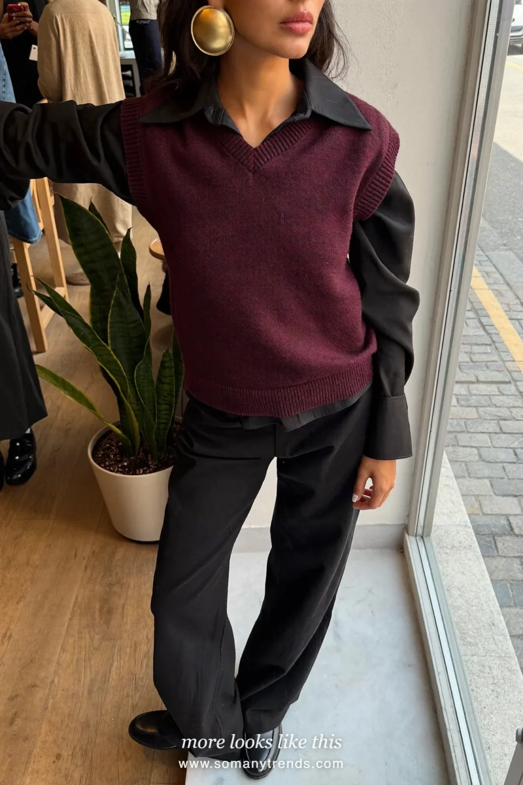 Woman in a burgundy knit vest over a black collared shirt, black wide pants and black loafers, outfit 19