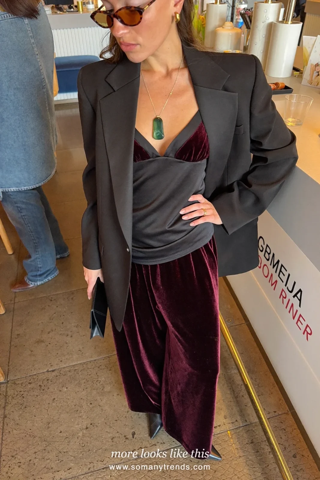 Woman in a black satin camisole top, burgundy velvet straight pants and black heeled boots, outfit 23