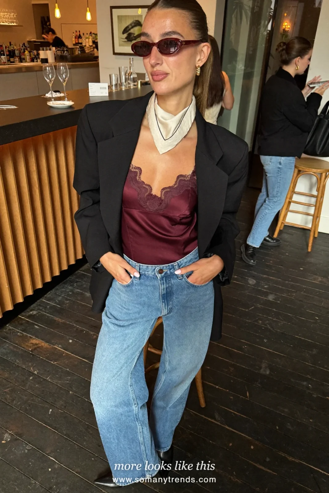 Woman in a burgundy lace-trim cami, black oversize blazer, light straight jeans and black pointed boots, outfit 26