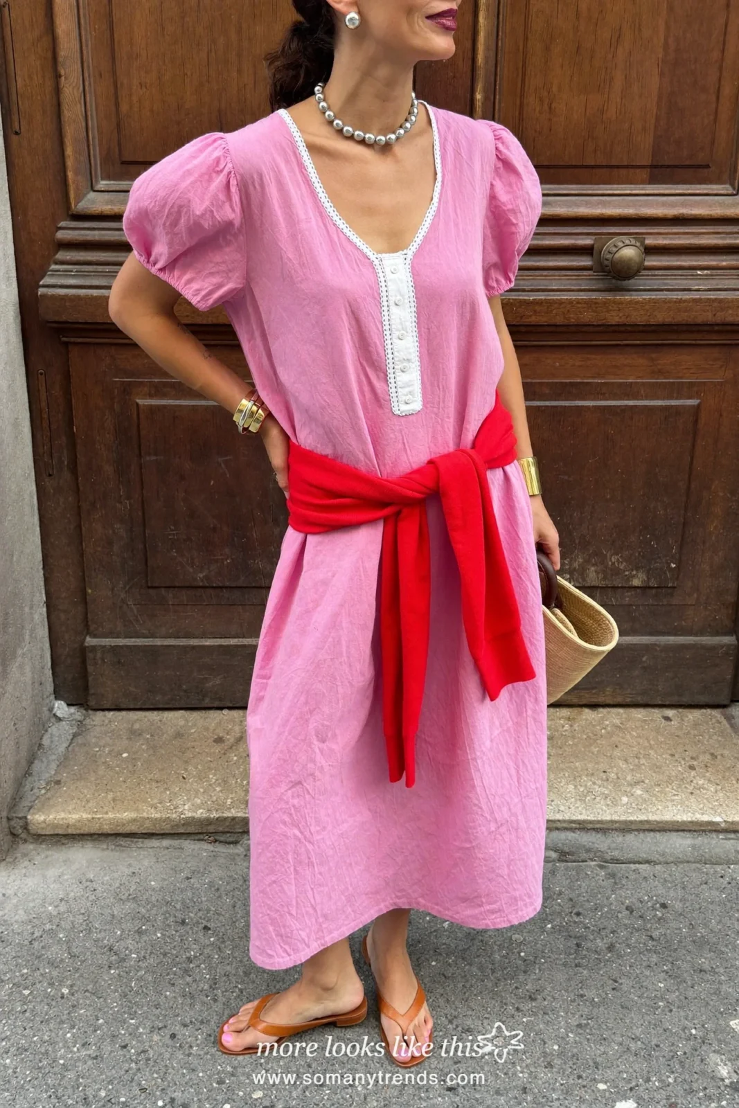 Pink crinkled midi dress, deep red sweater tied at the waist, tan flat sandals and straw bag, outfit 2