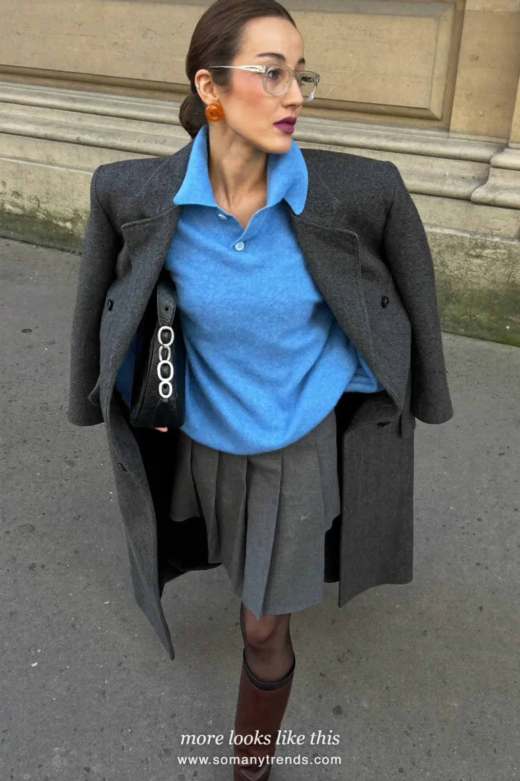 Woman in a baby blue knit polo, gray pleated midi skirt, sheer black tights, brown boots and a charcoal coat near an office, outfit 10
